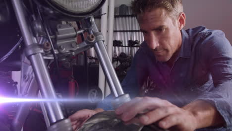 animation of glowing lights over caucasian male mechanic repairing motorbike in garage