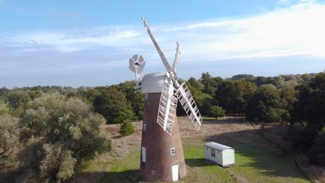 billingford windmill at farmland area with house and blue sky in diss, norfolk - drone flying slow shot