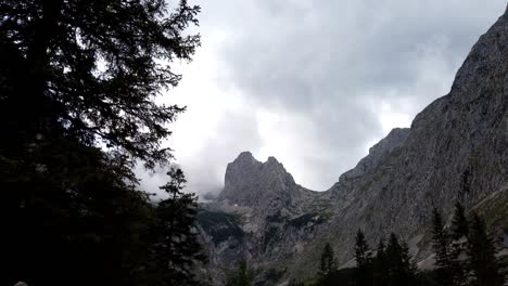 Timelapse,-moving-upwards,-showing-summit-of-german-alps-with-many-clouds-wrapping-around-with-light-beams-breaking-trough-a-couple-of-times