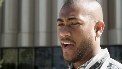 hombre afroamericano pensativo hablando en la calle