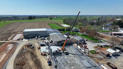 aerial shot of construction site with crane assembling steel beams showcasing rural pennsylvania landscape smooth motion cinematic quality rich detail