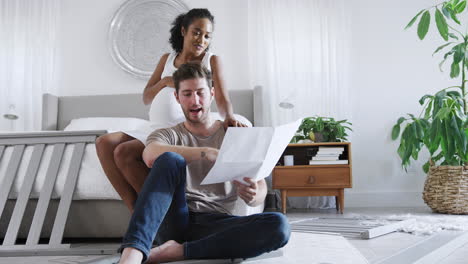 Interracial-Couple-With-Pregnant-Woman-In-Bedroom-Putting-Together-Self-Assembly-Baby-Cot