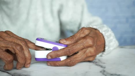 persona de edad avanzada que utiliza un oxímetro de pulso