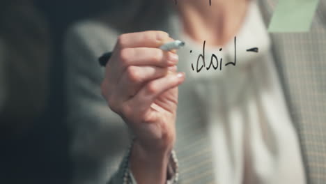 mano de primer plano, escritura y tablero de vidrio con mujer