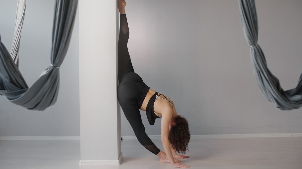 Woman doing a yoga stretch against a pillar in a yoga studio