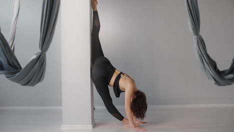 woman doing a yoga stretch against a pillar in a yoga studio