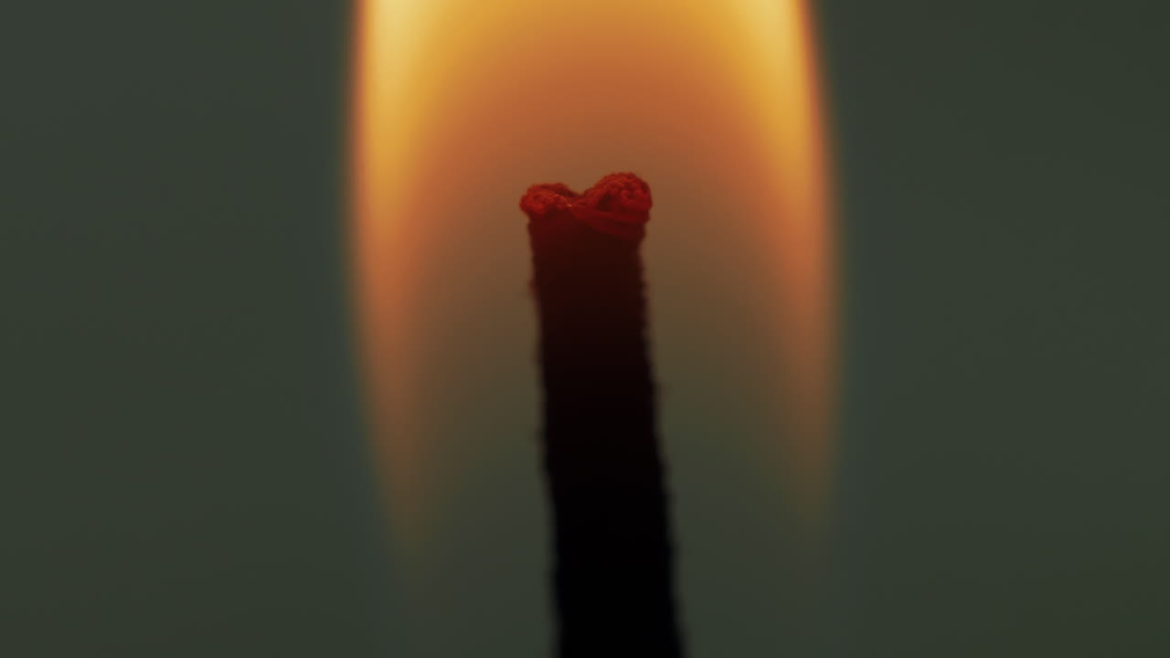 студийная макросъемка: горящий фитиль свечи и пламя, колеблющееся под действием ветра