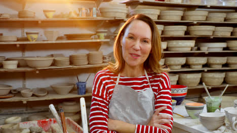 Female-potter-standing-with-arms-crossed-in-pottery-workshop-4k