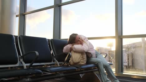 woman sleeping across airport chairs while waiting for flight a young traveler lies curled up across several chairs in the airport sleeping while waiting for departure