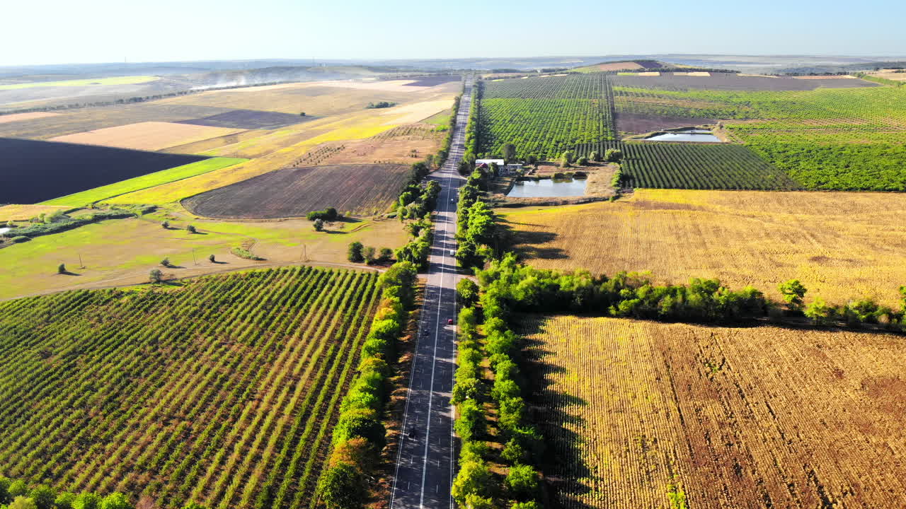 Aerial drone view of a road with moving car in highland. Green fields and hills from north part of Moldova