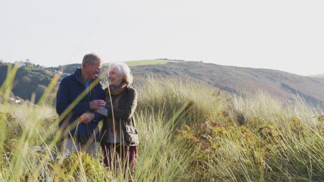 loving active senior couple walking arm in arm through countryside together