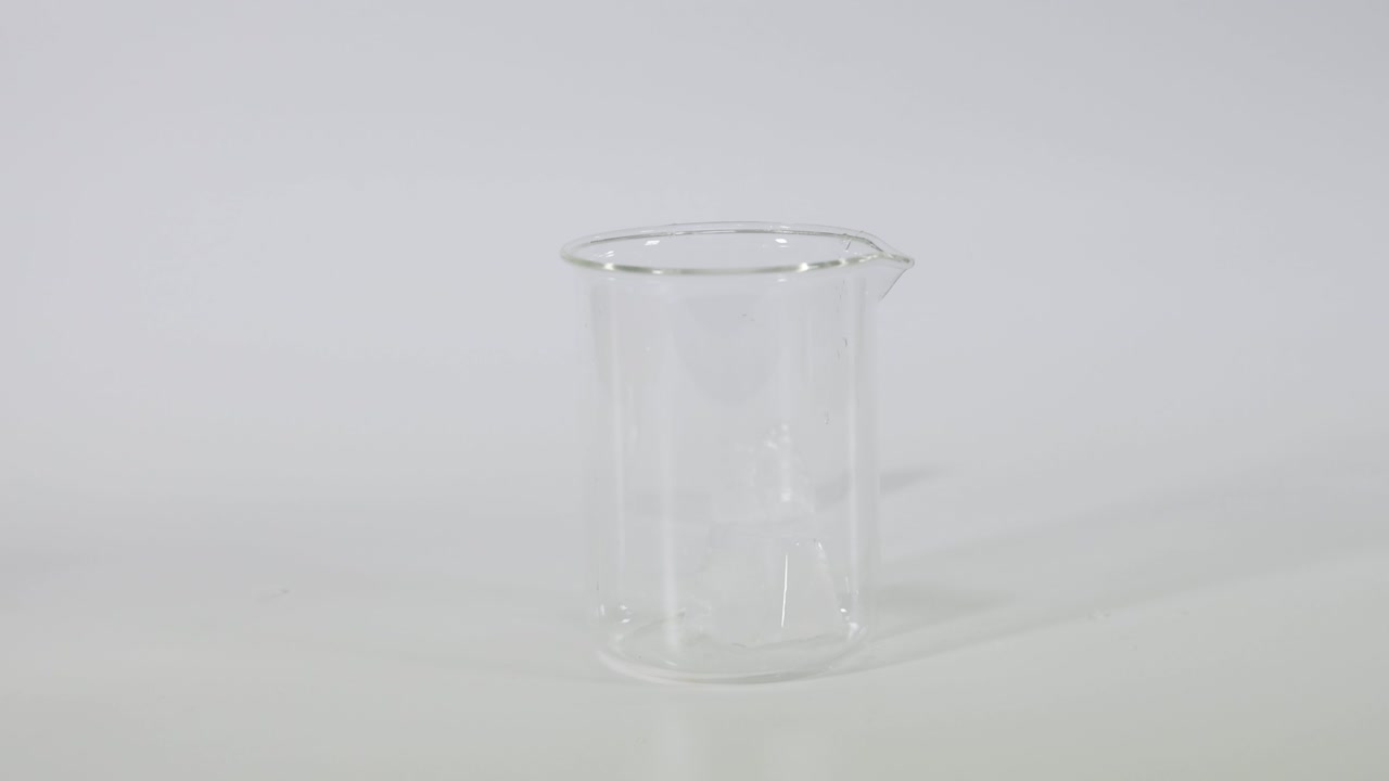 Ice cube falling into a glass beaker