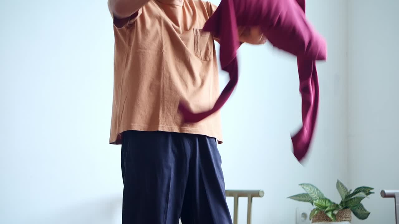 Elderly man carefully sorting laundry into woven basket when housework