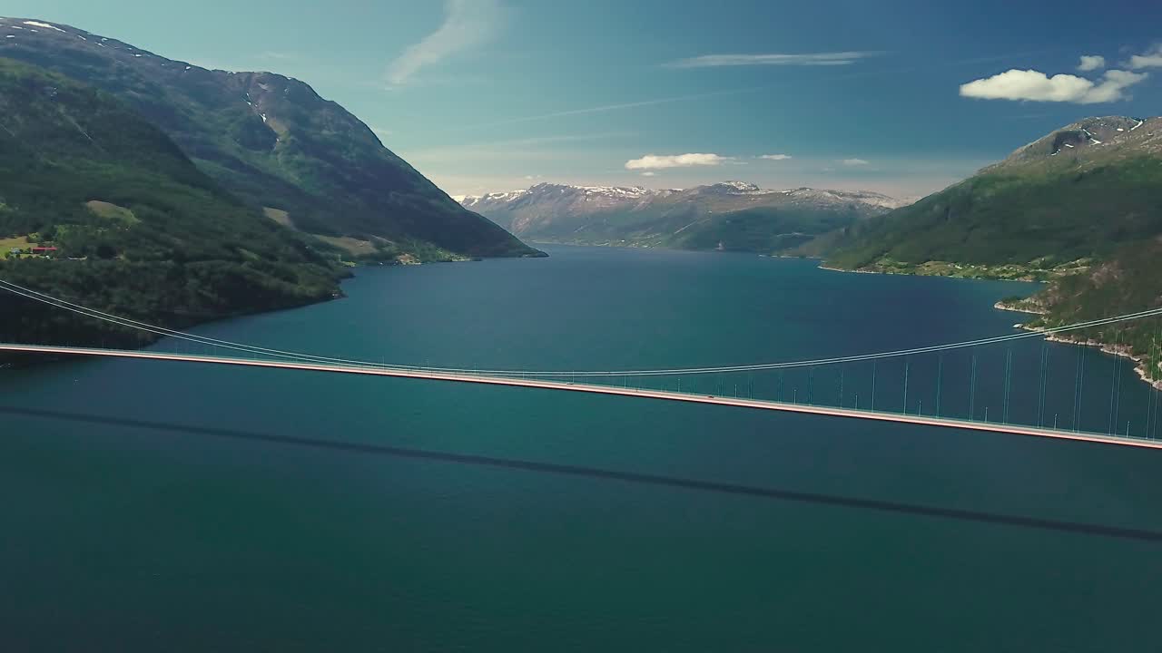 Panorerende afslørings-droneoptagelse af en hængebro på en solrig dag.