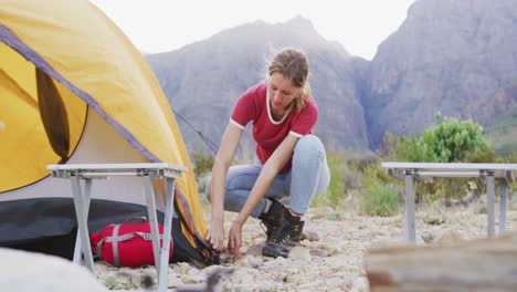 caucasian woman setting up camping tent