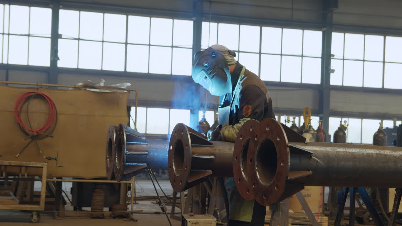 Soldador trabalhando em tubos de metal em uma fábrica