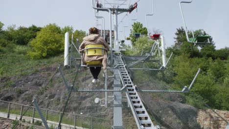 a woman riding on a small chair in a cable car at prague zoo in the czech republic