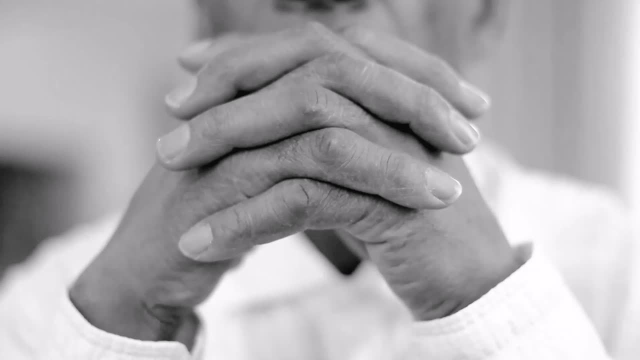 orando a dios con las manos juntas sobre fondo gris almacen de metraje de video