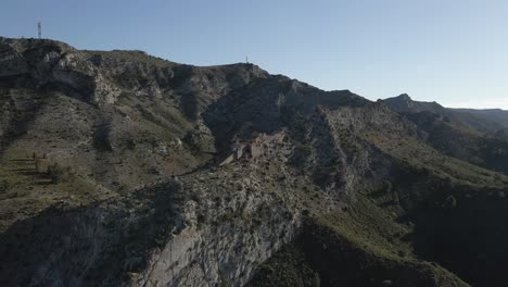 Fliegen-Sie-über-Trockene,-Raue-Felslandschaft-Zur-Steilhang-Einsiedelei-Kapelle