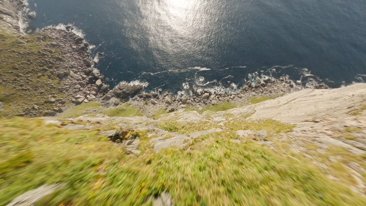 Mergulho impressionante de um penhasco de montanha debruçado sobre o mar na trilha Ryten, na Ilha de Lofoten, Noruega, voo de drone FPV.