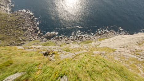 impressive dive of a mountain cliff overhanging the sea on the ryten hike in lofoten island, norway, fpv drone flight