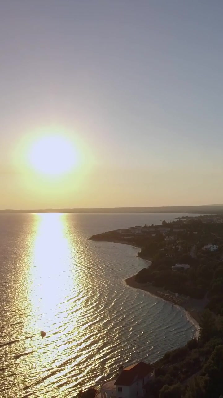 Aerial sunset scene of sea and coastline with houses in Trikorfo Beach, Greece