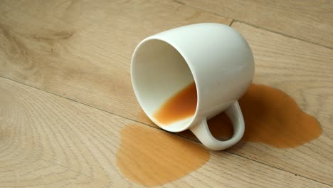 Cup-of-coffee-spilled-on-wooden-floor-,