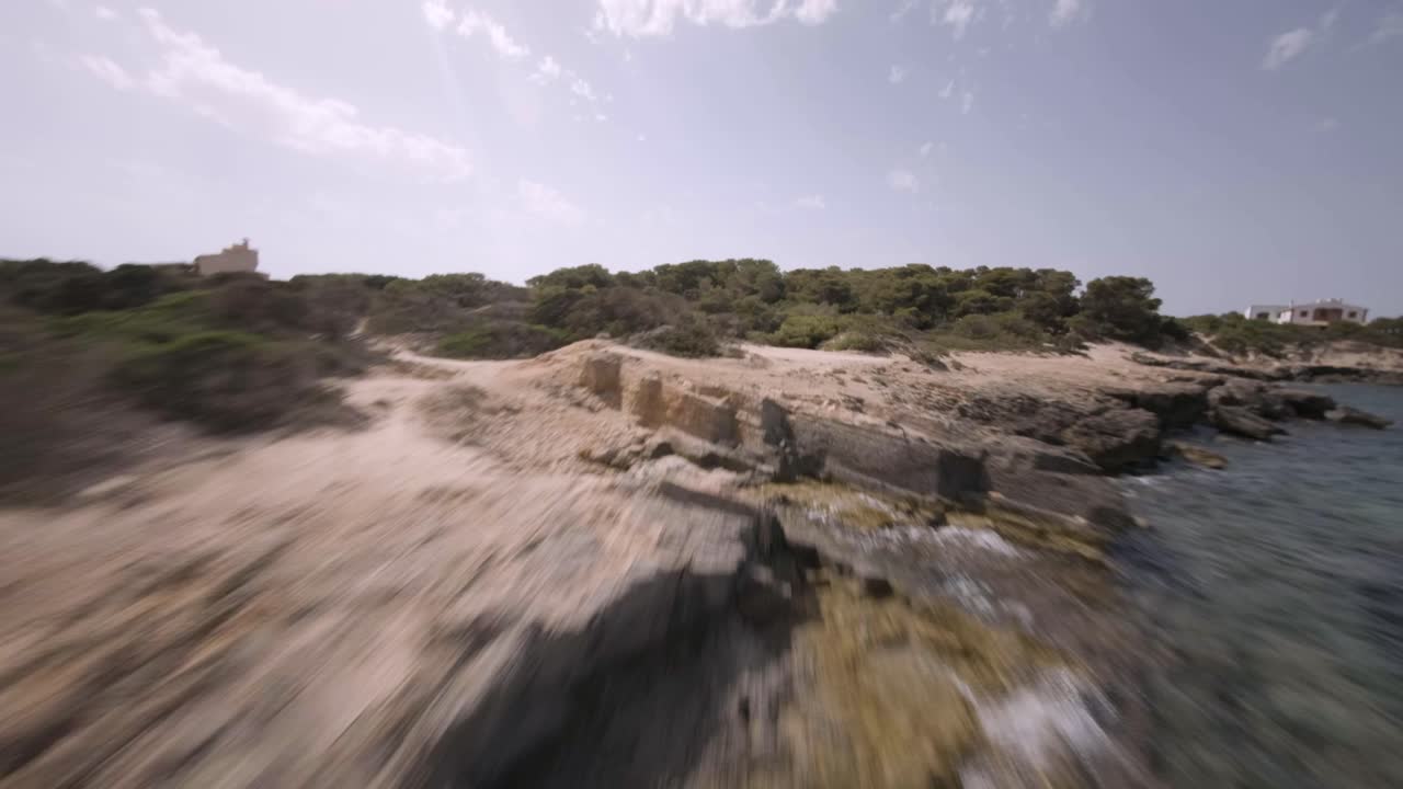 fpv drone disparó sobre tierras altas cubiertas de vegetación verde junto a playas rocosas en faro de s'estalella, mallorca, islas baleares, españa