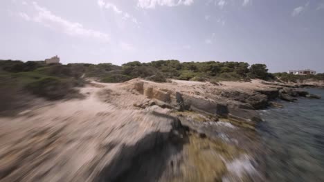 FPV-drone-shot-over-highlands-covered-with-green-vegetation-alongside-rocky-beaches-in-Faro-de-s'Estalella,-Mallorca,-Balearic-Islands,-Spain