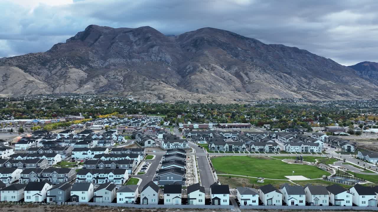 Vista aérea de la expansión de los suburbios que invaden las tierras de cultivo en Utah Valley, bajo el majestuoso monte Timpanogos. El paisaje captura el desarrollo suburbano y la belleza natural.