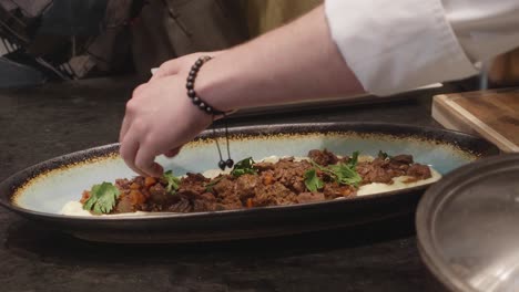 chef makes plating of a dish with mashed potato and baked meat