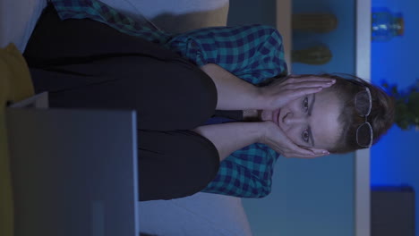 video vertical de una mujer viendo una película de terror en una computadora portátil por la noche. la mujer está asustada.