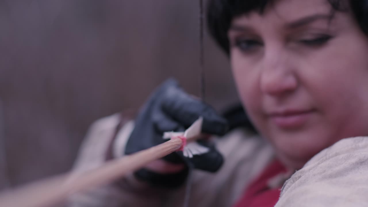 una mujer guerrera dispara un arco en el objetivo.