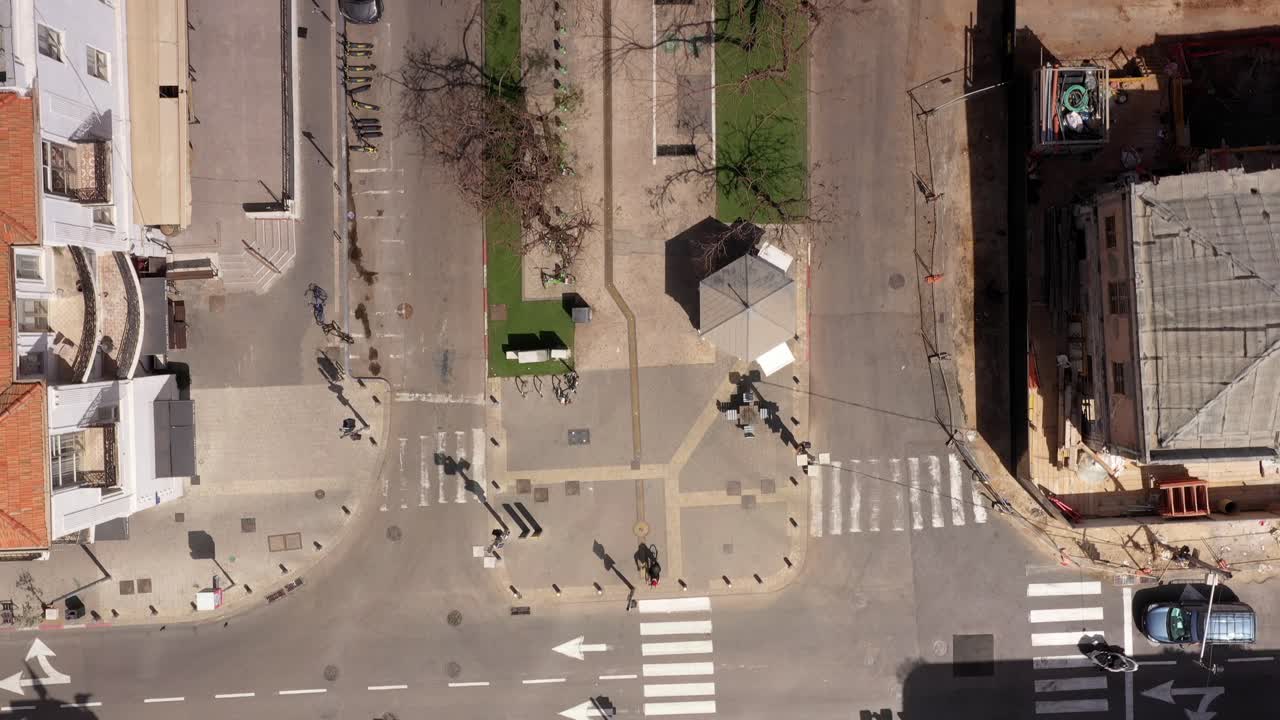 Aerial view of a city street intersection with buildings, a park, and construction