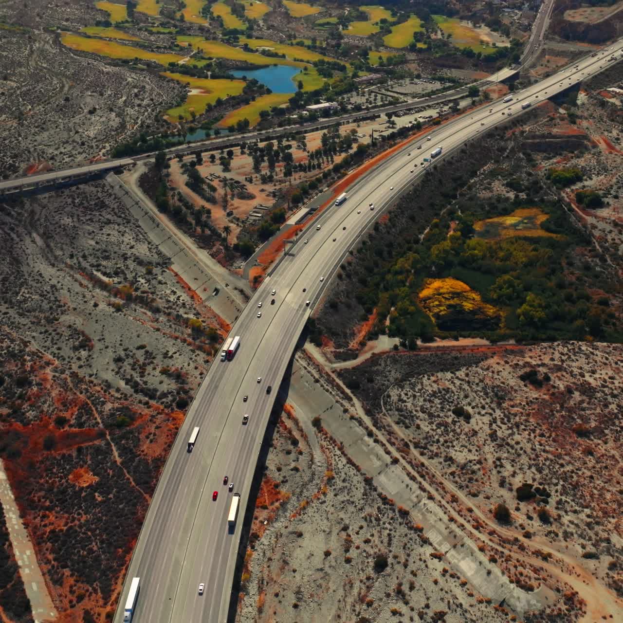 Rocky landscape with some islands of greenery. Multi-lane highway with transport moving by. Top view