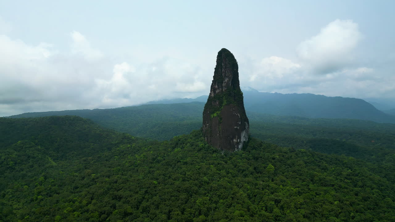 Drone flying backwards in front of the Pico Cao Grande mountain, in Sao Tome