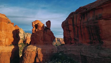 Drone-flying-through-massive-red-rock-spires-in-cliffs-then-revealing-mountains-in-Sedona