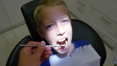 dentist examining a young patient with tools