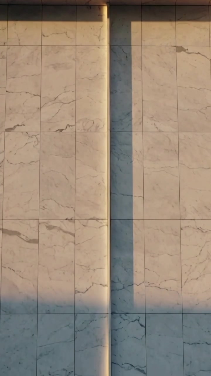 Vídeo vertical: Câmera inclinando revelando painéis de pedra centralizados em fachada urbana, para mostrar emenda iluminada.