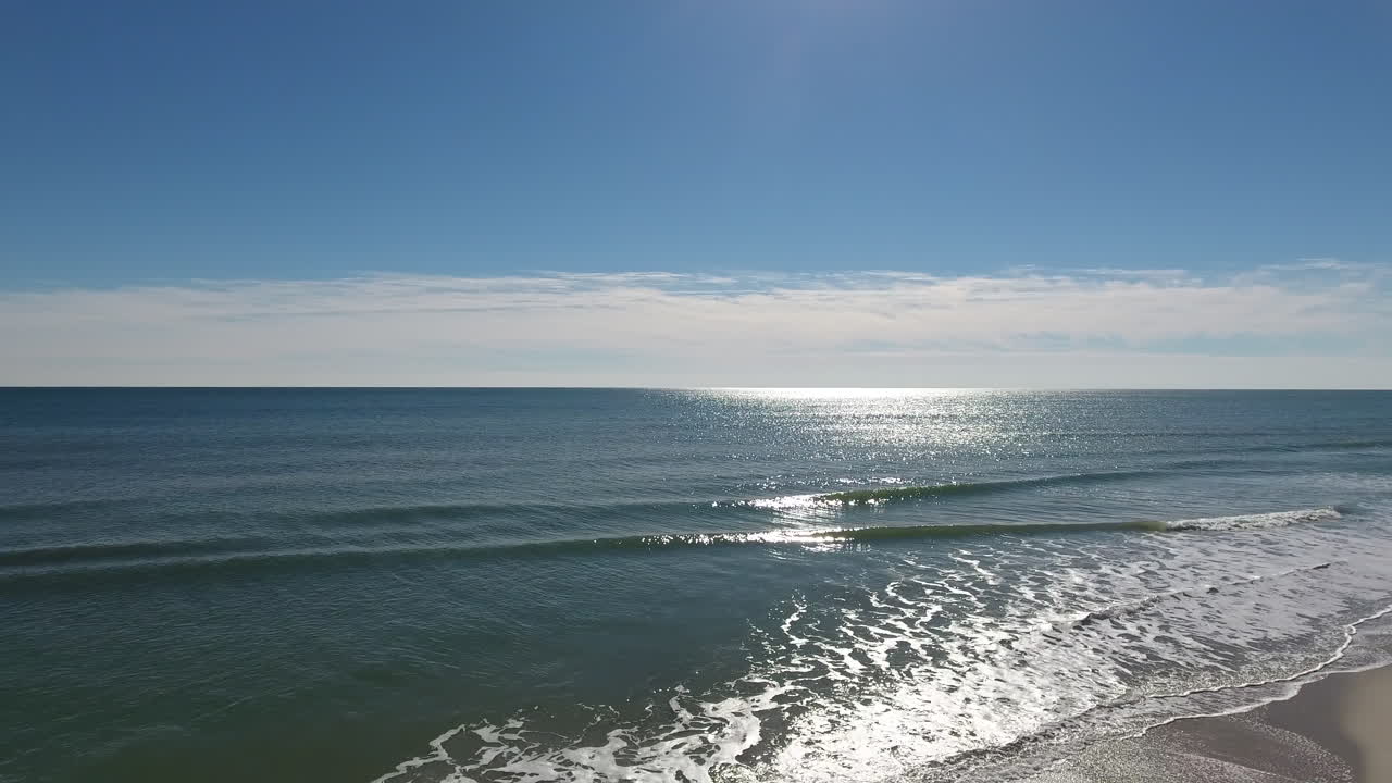 바다의 잔잔한 파도에서 해변을 향해 움직이는 드론 샷