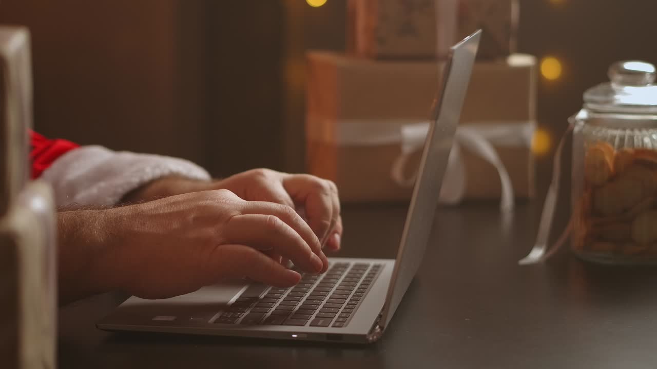 Santa Claus answers the child's email. Typing on the laptop keyboard. The camera pans around Santa. Close-up shot.