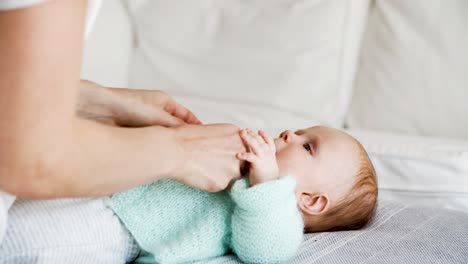mamá vistiendo a un bebé alegre en una chaqueta de lana