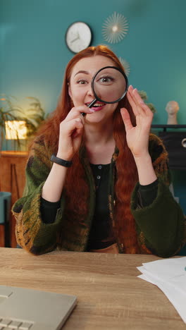 amazed woman holds magnifying glass near face looking at camera with big zoomed eye analyzing wow