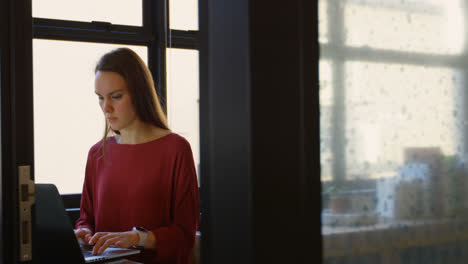 Front-view-of-young-caucasian-businesswoman-working-on-laptop-in-a-modern-office-4k