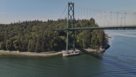 Vancouver-BC-Canada-Aerial-v105-drone-fly-under-the-Lions-Gate-Bridge,-capturing-the-urban-oasis-of-Stanley-Park-and-cityscape-with-ship-sailing-on-the-water---Shot-with-Mavic-3-Pro-Cine---July-2023