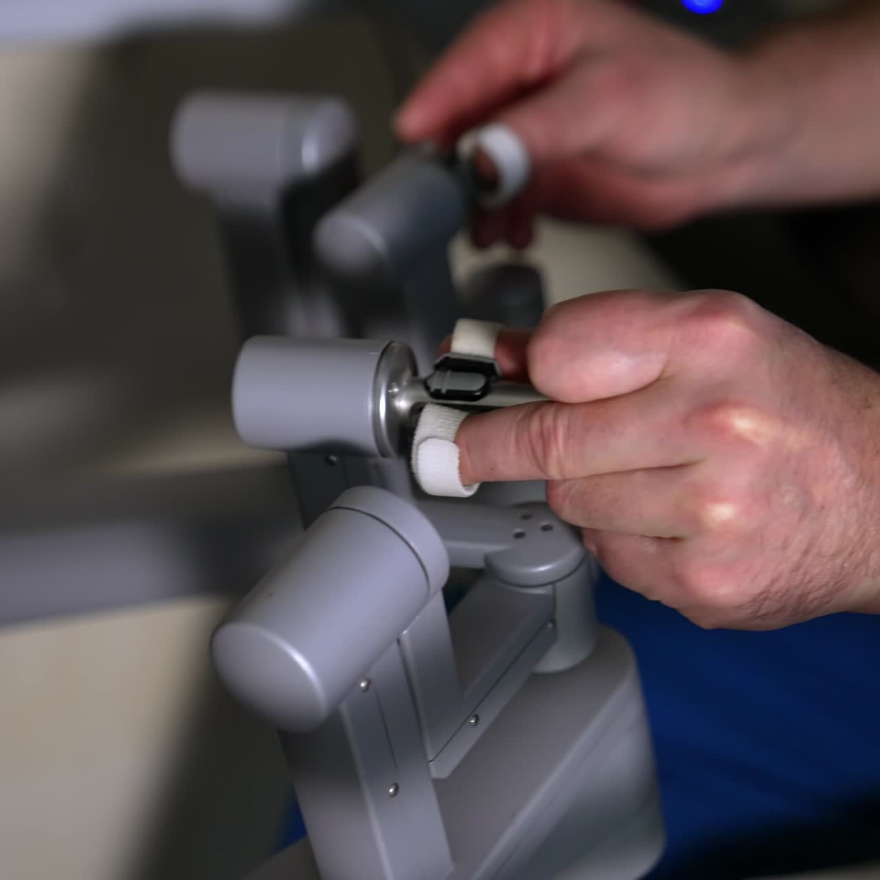 Male surgeon's hands manipulate the robotic arms. Medic moves slowly maneuvering technological equipment. Close up