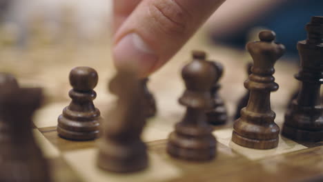 close-up of male fingers making first move on wooden chess board