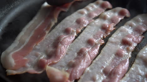 Hombre-Chef-Cocinando-Para-El-Desayuno-Un-Increíble-Tocino-Crujiente,-Rico-En-Grasa-Y-Color,-Chisporroteando-Y-Fumando-En-Una-Sartén-Caliente