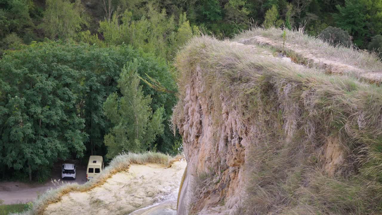 Natural spring water falling small rocky cliff side vegetation covered Bagno Vignoni Tuscany Italy