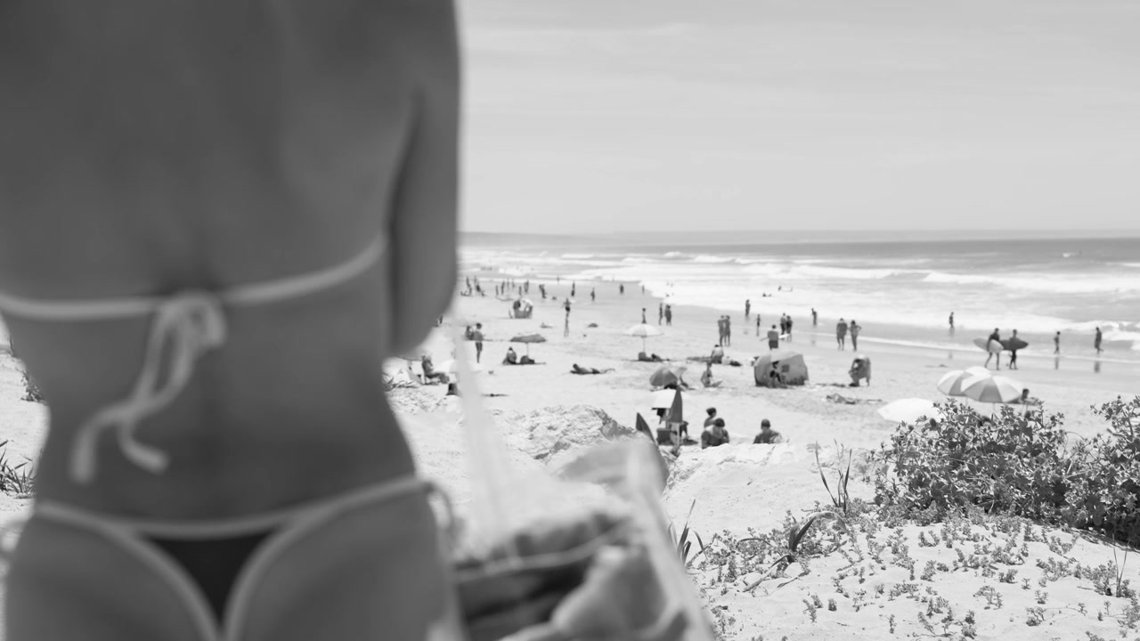 Vista in bianco e nero di una spiaggia affollata da dietro una persona